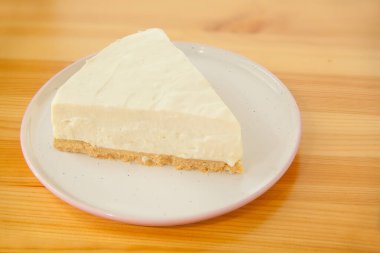 Tahta bir masada beyaz tabakta klasik cheesecake.