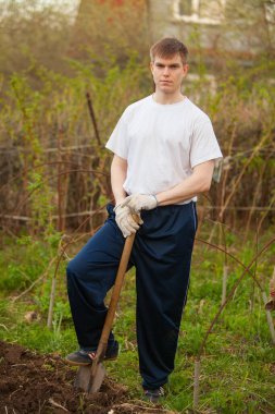 Ziraat Mühendisi güçlü yakışıklı çiçek yatak arka plan üzerinde kürek ile