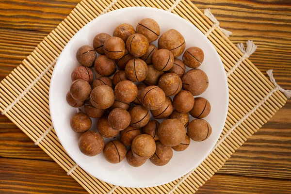 Köstliche Macadamia Nüsse Auf Einem Teller Auf Einem Hölzernen Hintergrund — Stockfoto