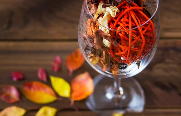Feuilles d'automne dans un verre à vin sur fond de table en bois — Photo
