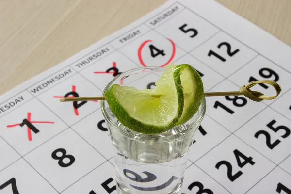 Red color writing on the calendar at friday with shot of tequila with a slice of lime — Stock fotografie