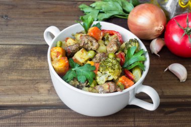 ahşap arka plan üzerinde malzemelerle seramik tencerede sebzeli biftek et Komposto