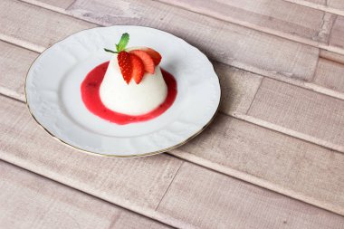 Panna cotta tatlı çilek sirup ve nane yaprağı ile
