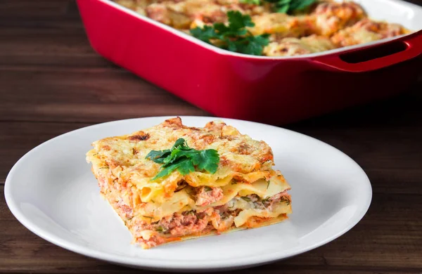 Close-up of a traditional lasagna topped with parskey leafs served on a white plate — Stock Photo, Image