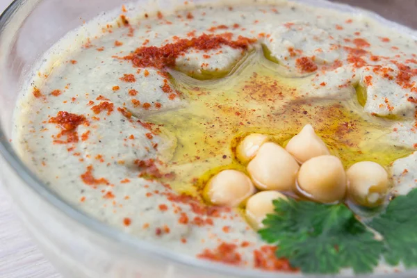 Close-up van een kom van romige hummus met olijfolie. — Stockfoto