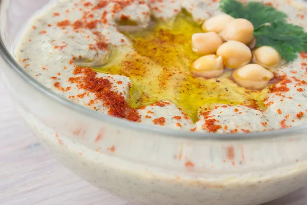 Close-up van een kom van romige hummus met olijfolie. — Stockfoto