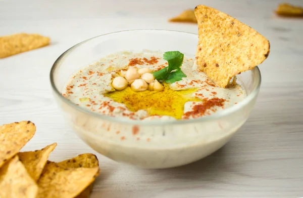 Uma tigela de hummus cremoso com azeite e batatas fritas . — Fotografia de Stock