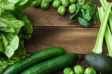 Folik asit - B9 vitamini içeren ürünler. Ahşap zemin üzerine yeşil sebze. Kereviz, avokado, Brüksel lahanası, fesleğen, salatalık, marul salatası