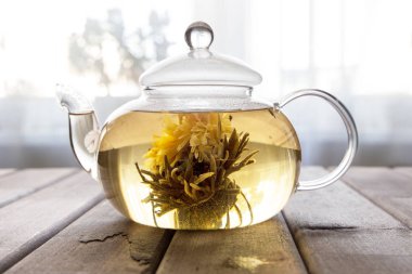 pencerenin önünde ahşap arka plan üzerinde çiçek Çin çay ile cam çaydanlık