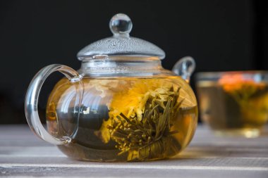 Çiçek Çin çay ve yeşil çay koyu arka plan önünde ahşap masa üzerinde bir kap ile cam çaydanlık