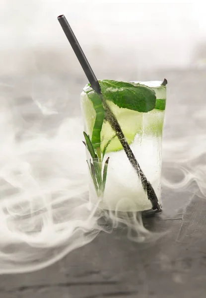 Glass with fresh cocktail made of ice in vapour on concrete table — Stock Photo, Image