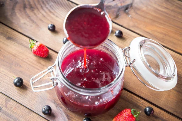 Pouring homemade berry jam into a jar — Stock Photo, Image