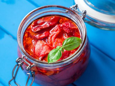 Kurutulmuş domates fesleğen mavi ahşap bir masa üzerinde bir cam kavanoza ile. Vejetaryen kavramı