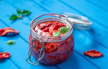 Kurutulmuş domates fesleğen mavi ahşap bir masa üzerinde bir cam kavanoza ile. Vejetaryen kavramı