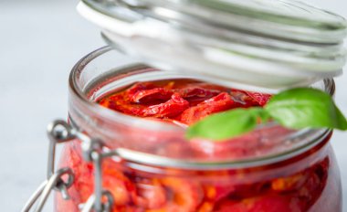 Kurutulmuş domates fesleğen beton bir tabloda bir cam kavanoza ile. Vejetaryen kavramı