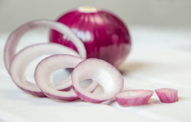 Beyaz ahşap arka plan üzerinde kırmızı soğan halkaları ve kırmızı soğan dilimlenmiş