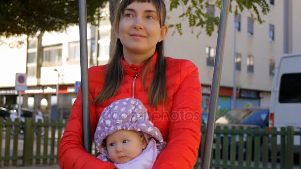 Máma držela dítě v náručí, houpání na houpačce v podzimní park — Stock video
