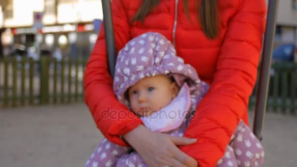 Baby op moeders handen swingen op de schommel in het najaar park — Stockvideo