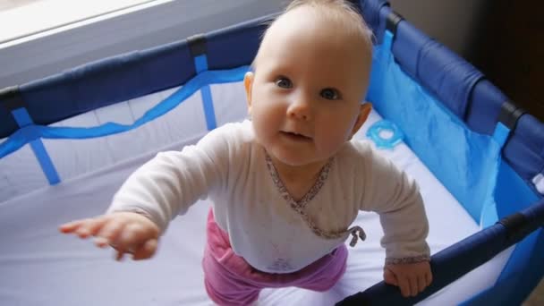 Bebé de pie en cuna sonriendo y mirando hacia arriba — Vídeos de Stock