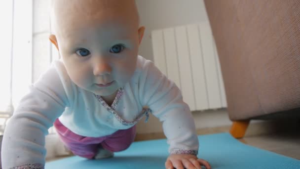 Baby with blue eyes trying to crawl on floor — Stock Video