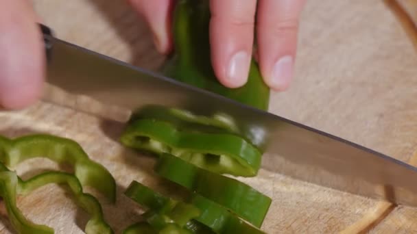 Mans hand skär paprika skivor med stor tandad kniv — Stockvideo