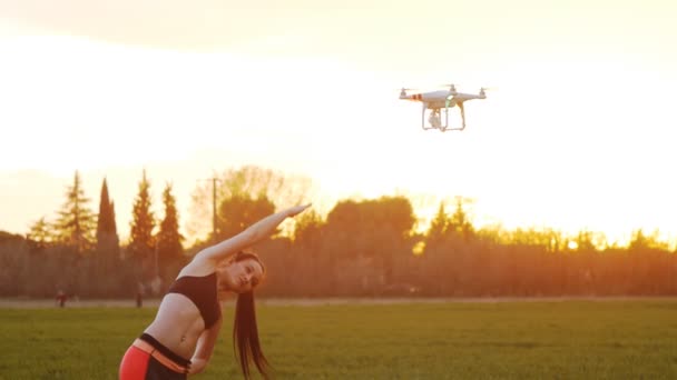 Vliegende drone met camera schiet fitness meisje doet kant bochten — Stockvideo
