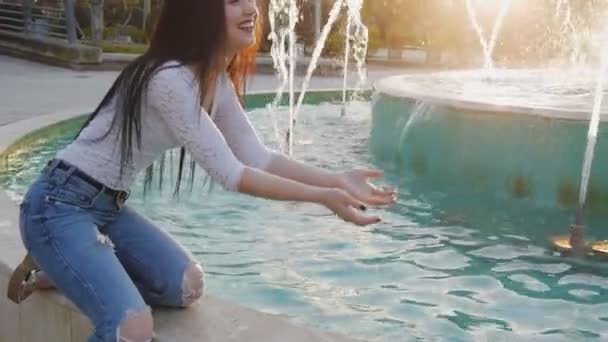 Mujer joven salpicando agua de la fuente — Vídeos de Stock