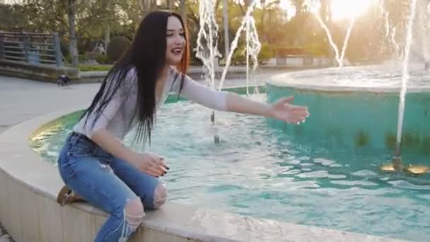 Ung kvinna stänk vatten från fontänen — Stockvideo
