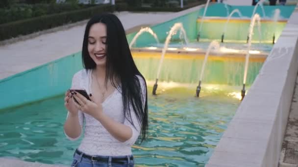 Meisje lacht en klapt haar met behulp van smartphone. — Stockvideo
