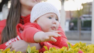 Yeşil yaprakları dokunmadan neşeli anne tutar bebek