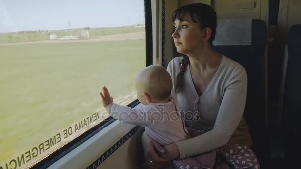 Молодая мать с ребенком на руках путешествует на поезде — стоковое видео
