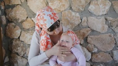 Genç anne bebeğini üzerinde koyarak güneş kremi krem