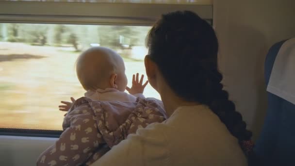 Νεαρή μητέρα με το μωρό στην αγκαλιά της, ταξιδεύουν με το τρένο — Αρχείο Βίντεο