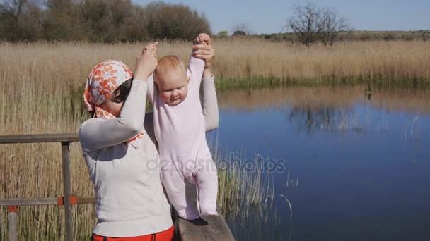 Moeder houdt handen van baby proberen te lopen — Stockvideo