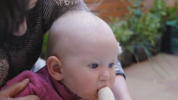 Ребенок ест банан из рук матери — стоковое видео