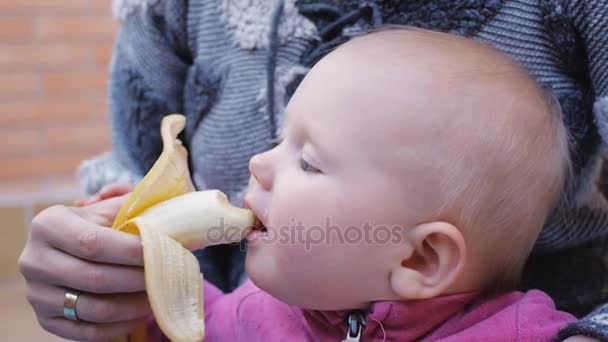 Baby eten van banaan uit handen van moeder — Stockvideo