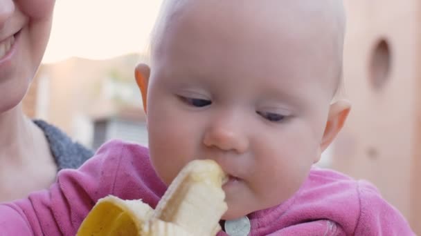 Baby isst Banane aus den Händen der Mutter — Stockvideo
