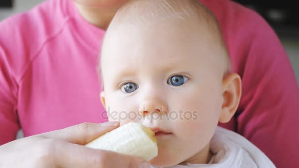 Ребенок ест банан из рук матери — стоковое видео
