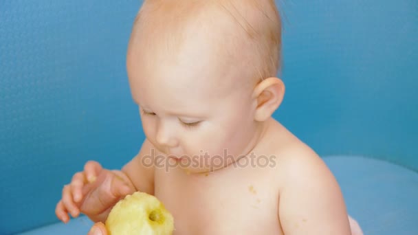 Bebé come manzana pelada sosteniéndola en ambas manos — Vídeos de Stock