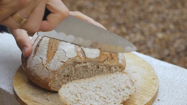 Мужские руки отрезали буханку хлеба — стоковое видео
