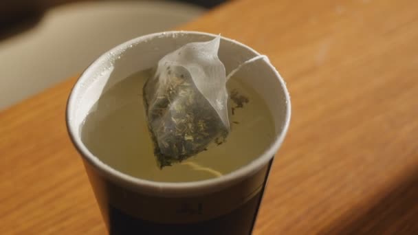 Close-up shot van groene thee in transparante piramide gebrouwen in papier beker — Stockvideo