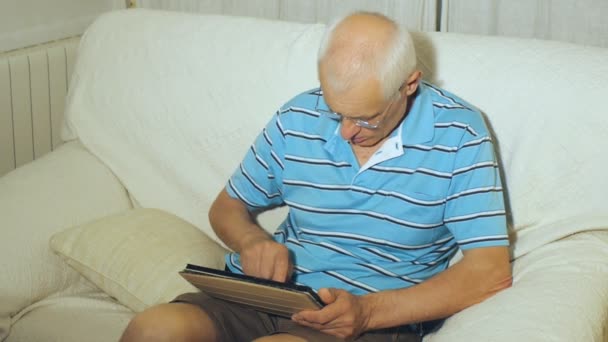 Hombre de edad avanzada utiliza tableta — Vídeo de stock