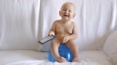 Bebek smartphone kullanarak lazımlık üzerinde oturur