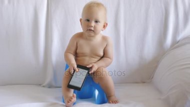 Bebek smartphone kullanarak lazımlık üzerinde oturur