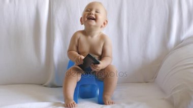 Bebek smartphone kullanarak lazımlık üzerinde oturur