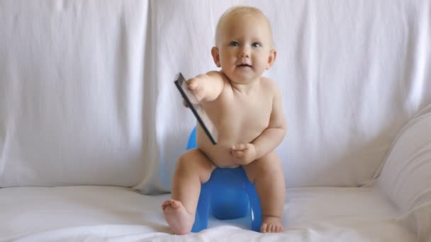 Baby sits on potty using smartphone — Stock Video