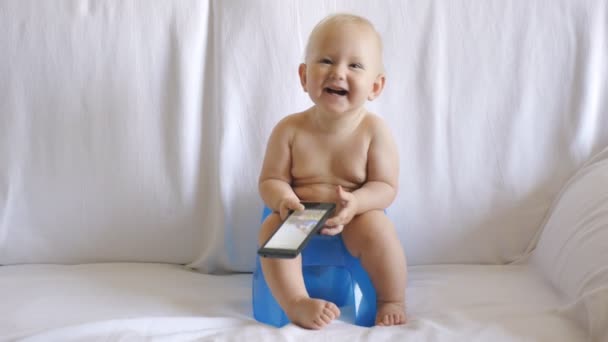 Baby sits on potty using smartphone — Stock Video