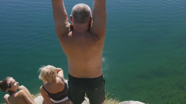 Большой человек прыгает в озерную воду — стоковое видео