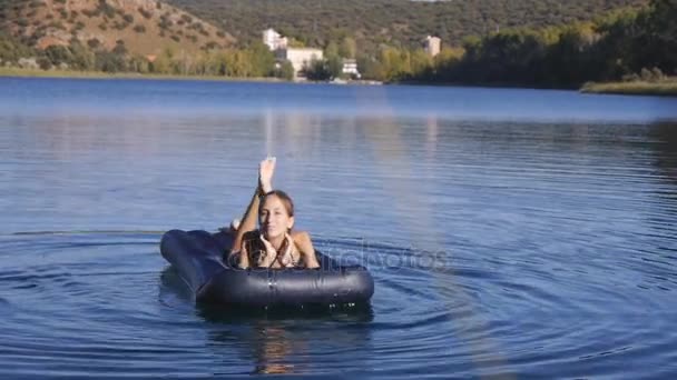 Young slim girl floats on inflatable mattress — Stock Video