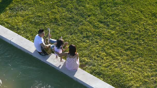 Сім'я з дитиною гуляє на зеленій траві — стокове відео